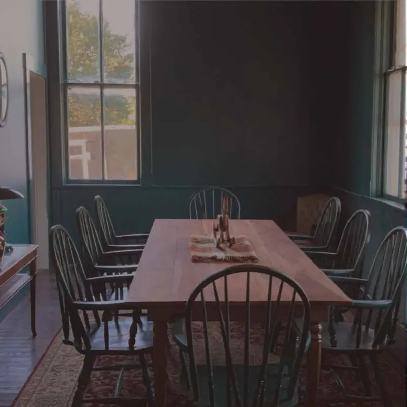 Dining room with Windsor chairs, a farm table and dark green walls