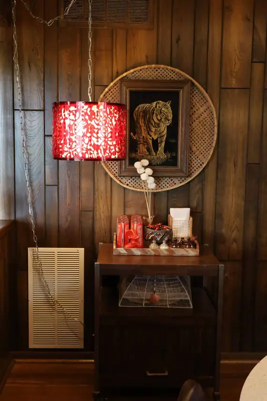 Bedside table with a red lamp and a tiger print on wood paneling