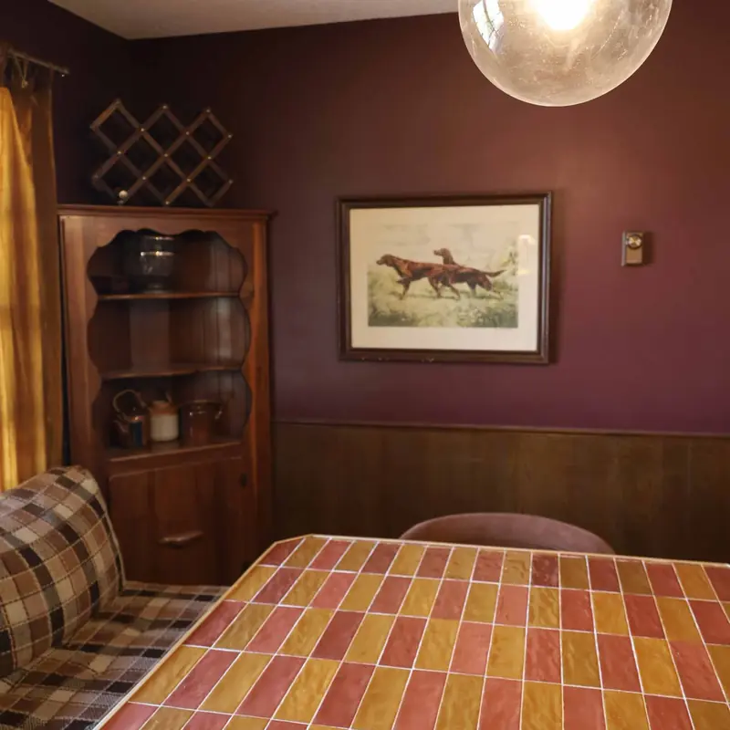 Dining nook with colorful tile, a globe pendant and a corner cabinet