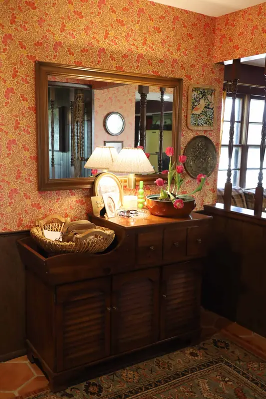 Entryway with floral wallpaper and a vintage secretary desk